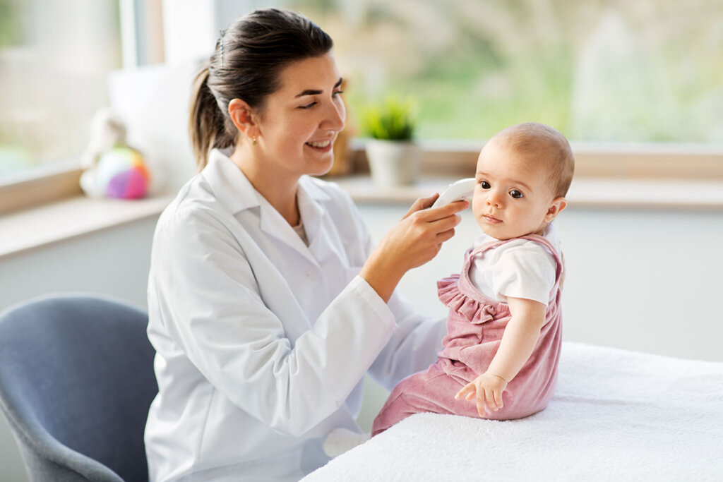 Pediatra tomando la temperatura a un niño pequeño