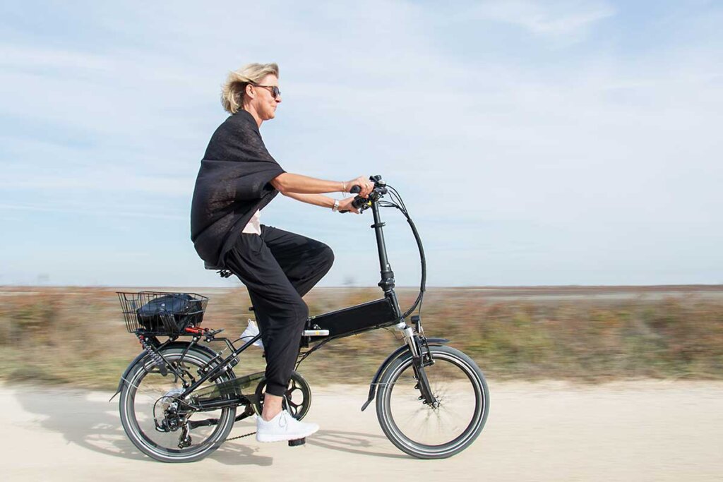 mujer montando en una e-bike plegable en la playa