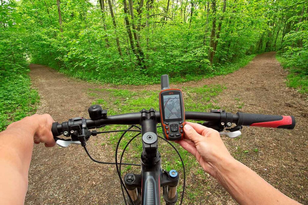 un ciclista mira su navi antes de cruzar un camino en el bosque