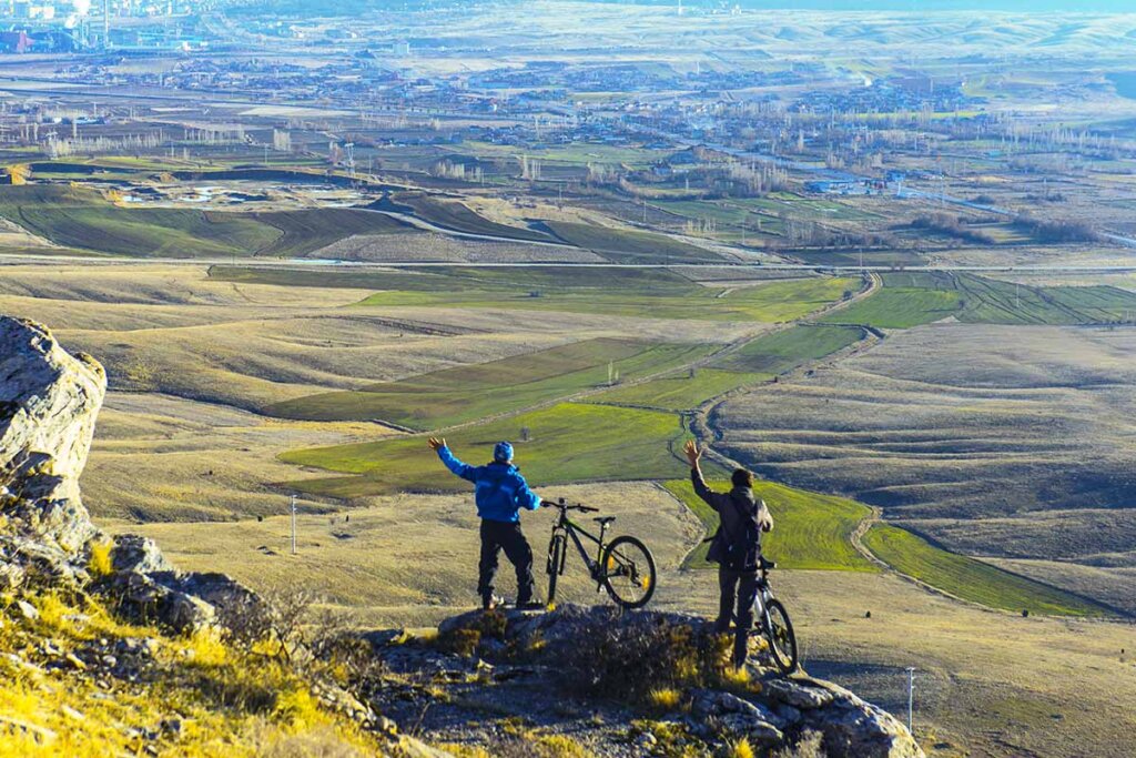 un ciclista se para en una montaña y contempla el paisaje