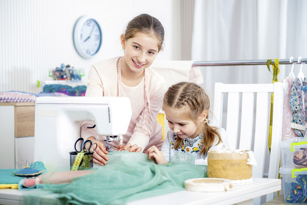 Los hermanos cosen con una máquina de coser infantil