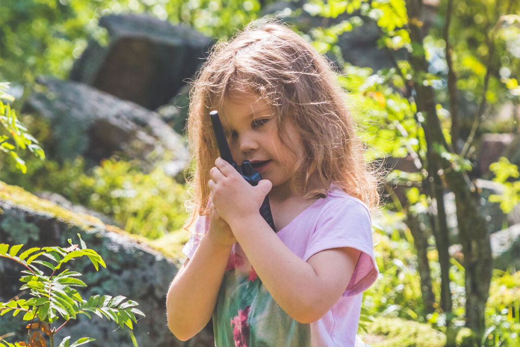 Niño hablando por un walkie-talkie en el bosque