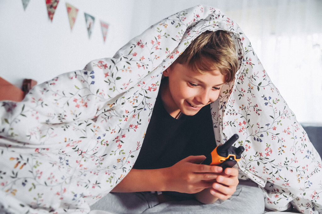 Niño jugando con un walkie-talkie en la cama