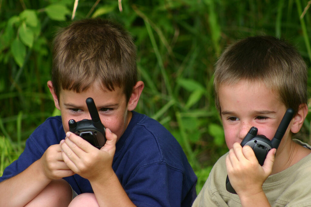 Dos niños jugando con walkie-talkies al aire libre