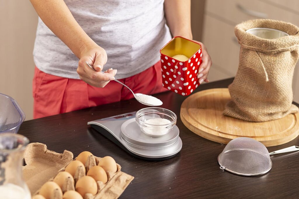 Mujer midiendo azúcar en la cocina