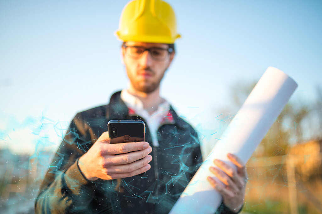 trabajador de la construcción con casco sostiene un smartphone para exteriores en la mano