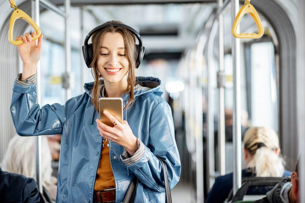 Mujer joven en tren con auriculares en la cabeza