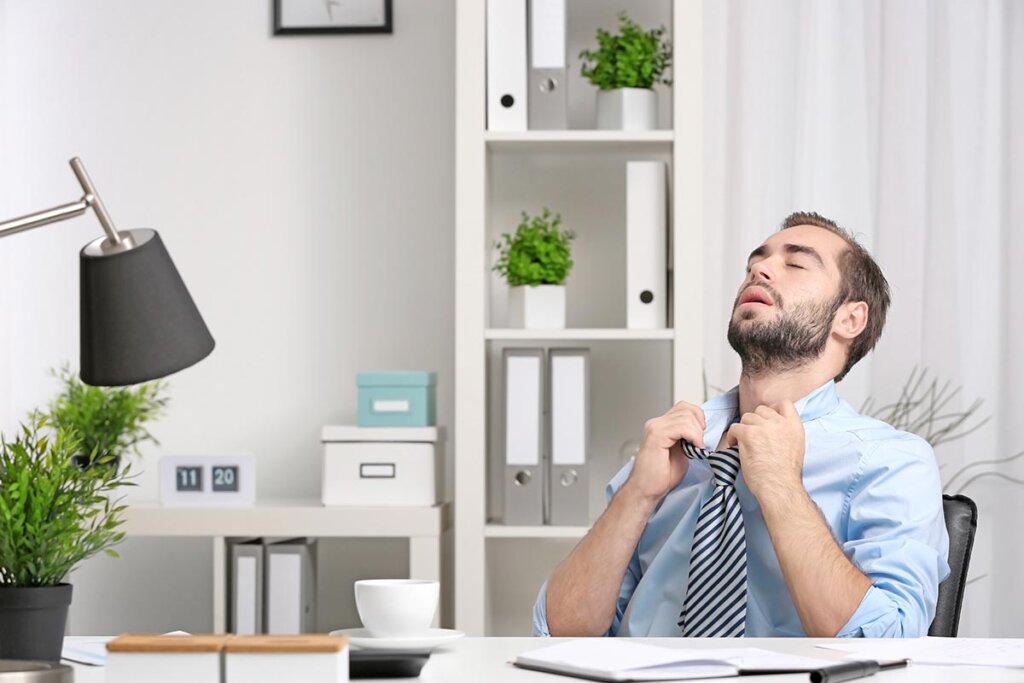 Hombre sentado en la oficina sudando