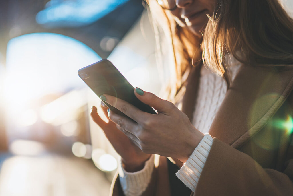 Mujer sosteniendo un smartphone en una estación de tren