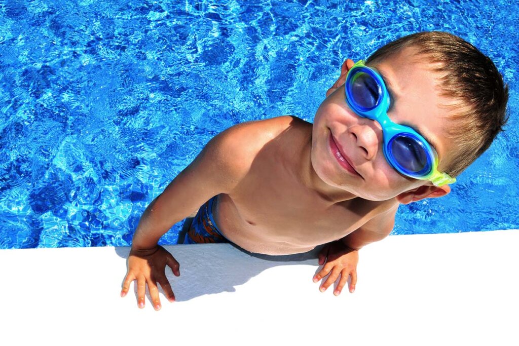 Niño con gafas de natación sale de la piscina