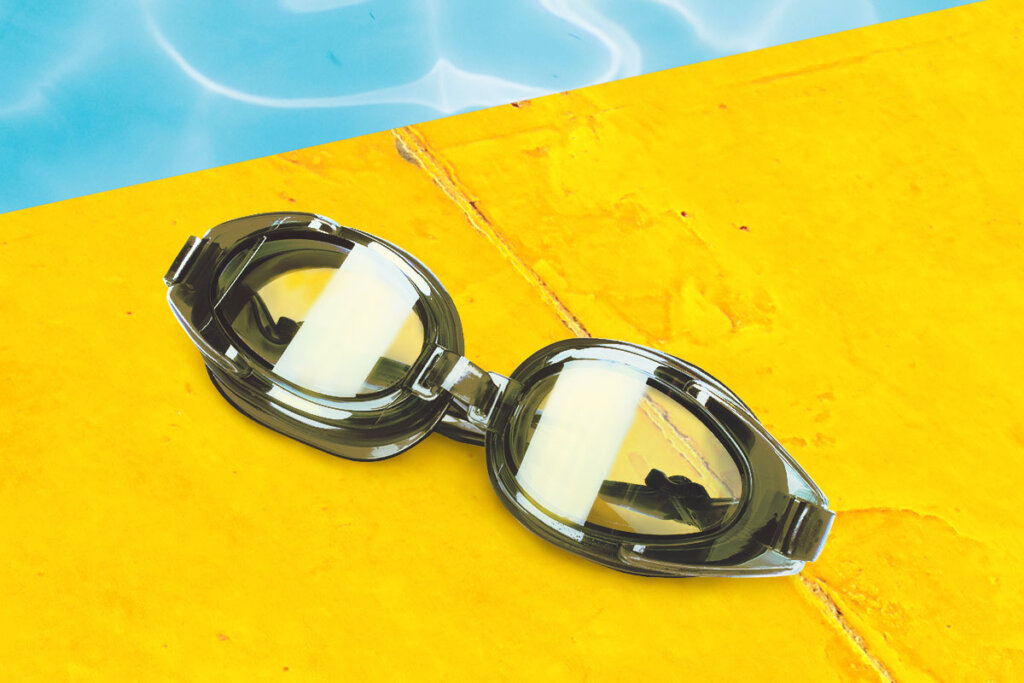 Gafas de natación en el borde amarillo de la piscina