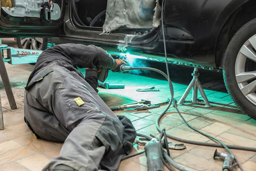 Persona en un taller soldando en un coche